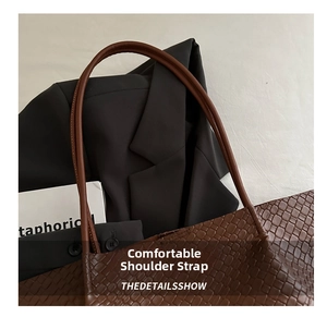 Detail shot of the comfortable brown leather woven shoulder strap on a tote bag