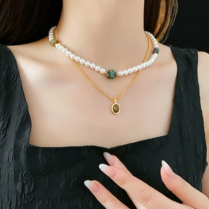 Gros plan d'un collier à deux rangs avec perles, chaîne dorée et pendentif oeil-de-tigre