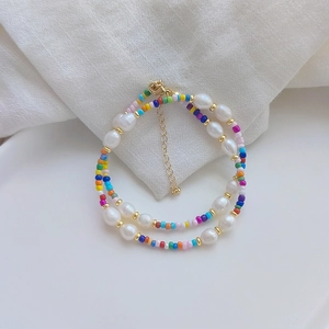 Colorful beaded necklace with natural pearls and gold clasp on white linen background