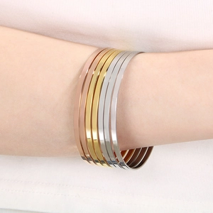 Detail of six minimalist stacked titanium steel bangles in gold, silver, and rose gold