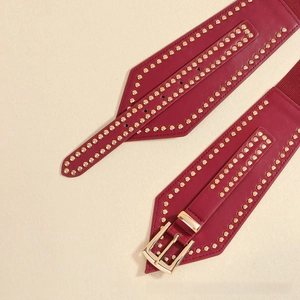 Close-up of wine red wide belt with gold studs and rectangular pin buckle detail