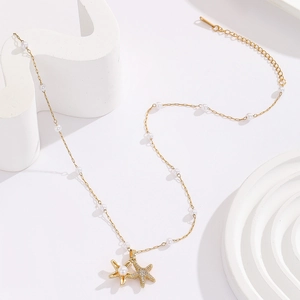 Macro shot of 18K gold-plated starfish charms and pearls on a fine link necklace