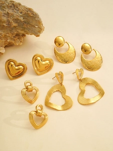 Detail van een gouden hart oorbellen set met hamertextuur en glad gepolijste afwerking