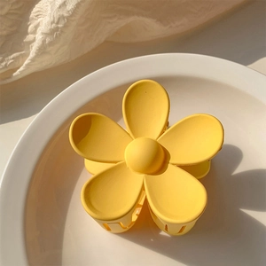 Close-up of yellow flower hair claw clip with matte finish on white ceramic plate