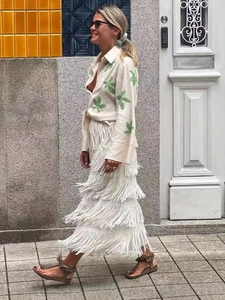 Schicke Damenbluse mit Blattmuster und weißem Fransen-Maxirock für den modischen Herbst-Look