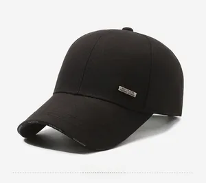 Detail of black baseball cap featuring silver metal logo plate and embroidered visor edge