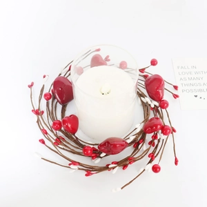 Close-up of red heart berry wreath centerpiece with white candle in glass holder