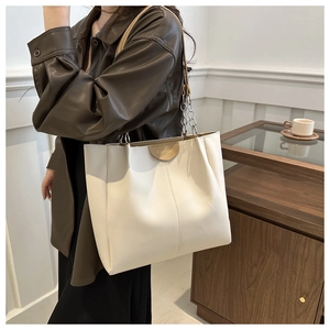 Dettaglio di una borsa tote color crema in ecopelle con toppa Fashion e tracolla a catena