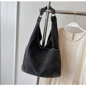 Detail of black washed denim hobo bag showing textile texture and metal ring buckle