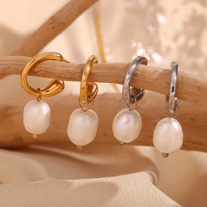 Detail of 18K gold and silver hoop earrings with freshwater pearls on a wooden branch