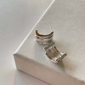 Minimalist 925 sterling silver curved C-shaped earrings on a beige display stand