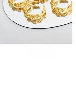Vue détaillée de bagues torsadées plaquées or avec un design élégant sur une surface miroir