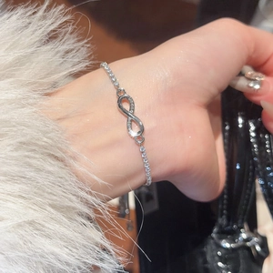 Close-up of a silver infinity bracelet with sparkling zircon stones on a woman's wrist