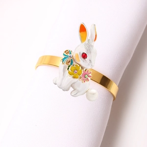 Detailed view of enamel bunny napkin ring with crystals and pearl on a white napkin