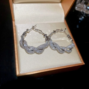 Detail of silver paved zircon hoop earrings in woven design inside an orange jewelry box