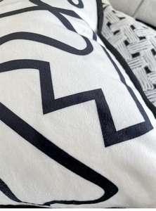 Close-up of velvet throw pillow featuring a bold black geometric pattern on white fabric