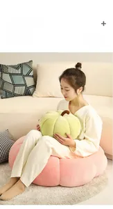 Detail of light green and pink corduroy pumpkin pillows on a cozy sofa