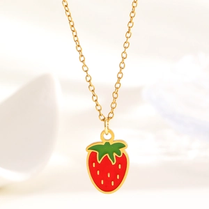 Macro shot of sweet strawberry pendant necklace with vibrant red enamel and gold chain