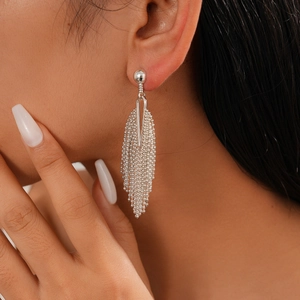Close-up of elegant silver tassel earrings with delicate beaded chains on model