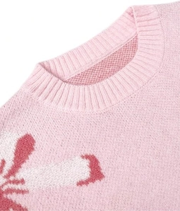 Close-up of pink knit sweater showing detailed bow jacquard texture and crew neckline