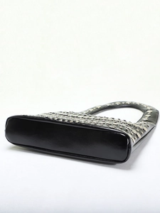 Detail view of black glossy leather handbag with silver stud rivets and punk style contour