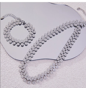 Detail of silver textured multi-circle link necklace and bracelet set on a mirror surface