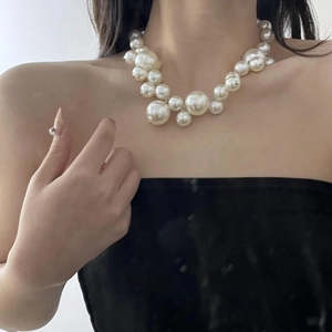 Detail of layered bohemian necklace with varying sizes of round pearls on a model