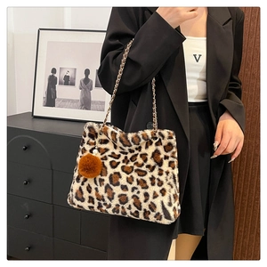 Close-up of leopard print plush tote bag with gold chain strap and brown fur ball charm