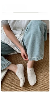 Close-up of beige polka dot low cut socks worn by model in a cozy indoor home setting
