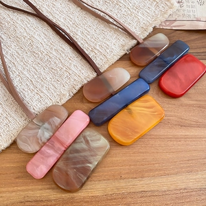 Detail of acrylic geometric square pendants with marble texture on minimalist leather cords