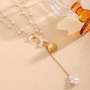 Detailed macro view of a gold shell pendant with a large baroque pearl on a chain