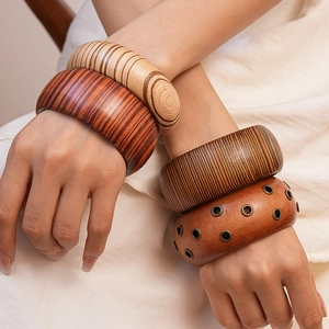 Detailed view of stacked wide wooden bangles with natural grain and metal eyelet studs