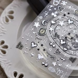 Detail of silver metallic nail stickers with heart and star patterns on ceramic tray