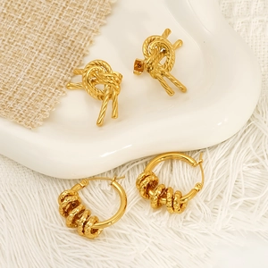 Elegant gold woven knot earrings and textured hoop sets on white ceramic tray