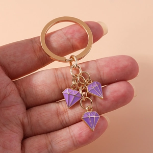 Detail of gold alloy keychain with three purple enamel diamond pendants on ring