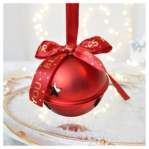 Macro shot of matte red Christmas bell with star cutouts and festive gold ribbon