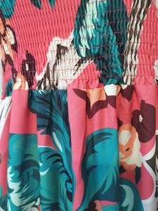 Detail of summer dress featuring tropical floral print and elastic smocking texture