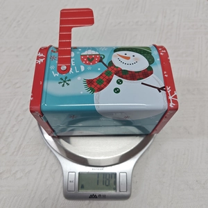 Gros plan détaillé d'une boîte aux lettres de Noël en fer blanc pesant 118,7g sur balance