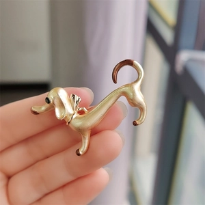 Detail of a gold dachshund brooch with brown enamel accents and a small black gem eye