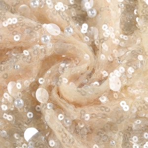 Close-up of champagne evening dress fabric with elegant sequins and pearl embroidery