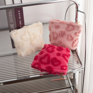 Detail of plush heart-pattern pouches in beige, pink, and rose with metal zippers