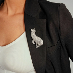 Detailed close-up of a vintage silver dog brooch pinned to a black blazer lapel