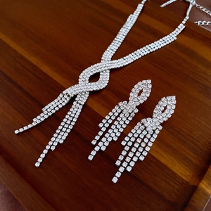 Close-up of sparkling rhinestone tassel necklace and earrings set on wood display tray