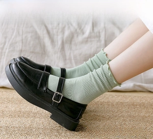 Detail of light green ruffled cotton socks with Mary Jane shoes and vertical knit texture