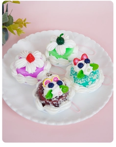 Detailed view of four colorful mini resin cake charms with cream and fruit decor