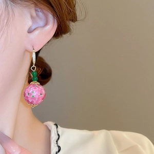Close-up of elegant pink glass bead earrings with green spots on a model's ear