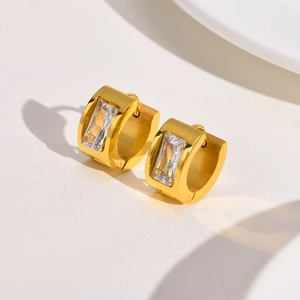 Detail of gold wide hoop earrings with baguette cut zircon and brushed metal finish
