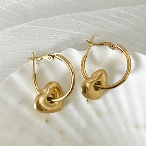Golden stainless steel C-shaped earrings with 3D heart pendants on a white shell background