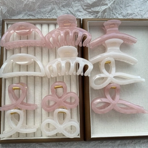 Assorted jelly-colored hair claws in pink and cream beige tones displayed in jewelry boxes