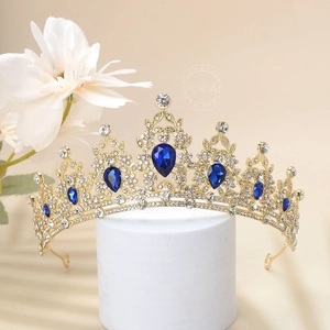 Detail of luxury baroque crown with blue teardrop stones and rhinestones on white stand